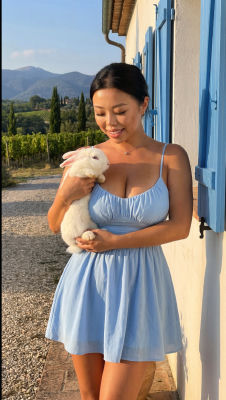 AI-generated image of a woman in a blue sundress holding a white rabbit in a vineyard setting