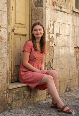 AI-generated image of a young woman in a pink dress by a yellow door