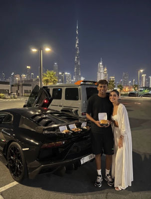 AI-generated image of two people beside a Lamborghini with the Dubai skyline at night