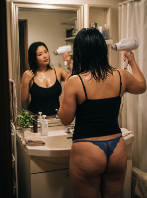 AI-generated image unidentified woman drying hair in a bathroom mirror