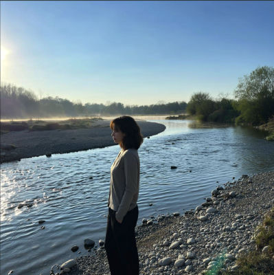 AI-generated image of a woman standing by a misty river at sunrise