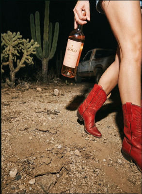 AI-generated image of a person holding a bottle of XOLO rosé wine in a desert at night