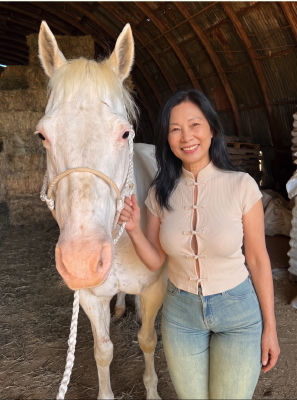 AI generated image of an unidentified woman  standing beside a white horse in a barn