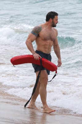 AI-generated image of Ben Affleck carrying a red rescue buoy at the beach