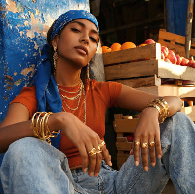 AI-generated portrait of a woman in gold jewelry and a blue headscarf at a market