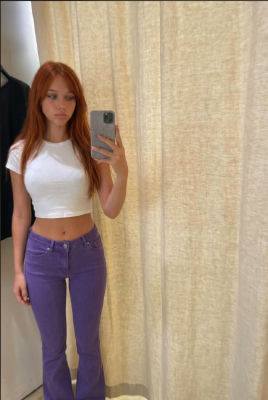 AI-generated mirror selfie of a young woman in a white crop top and purple jeans