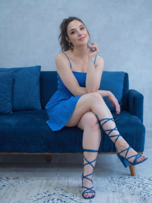 Deepfake of Gal Gadot seated on a blue couch in a blue sundress