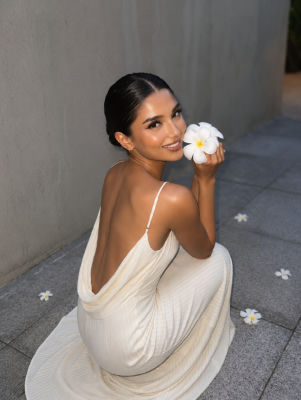AI-generated portrait of a woman in a white dress holding a plumeria flower