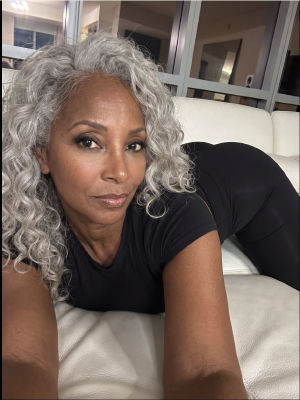 AI-generated image of a woman with curly gray hair on a white couch