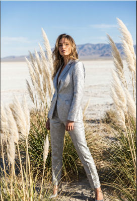 AI-generated image of a woman in a silver suit standing among pampas grass