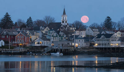 AI-generated coastal New England town with oversized full moon over harbor