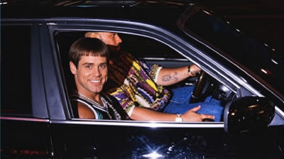 Deepfake of Jim Carrey smiling in a car beside a bearded driver