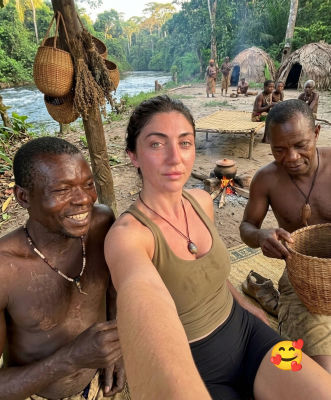 AI-generated meme featuring a woman in a riverside village selfie with heart-eyes emoji