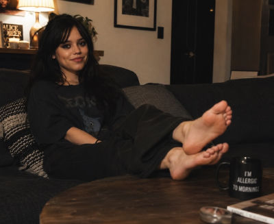 AI-generated image of Jenna Ortega relaxing on a couch with bare feet propped up