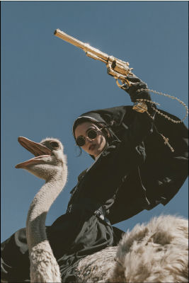 AI-generated image of a nun in dark sunglasses riding an ostrich with a gold revolver