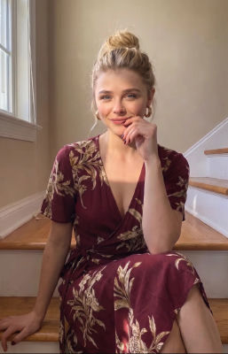 Deepfake of Chloë Grace Moretz seated on stairs in a floral wrap dress