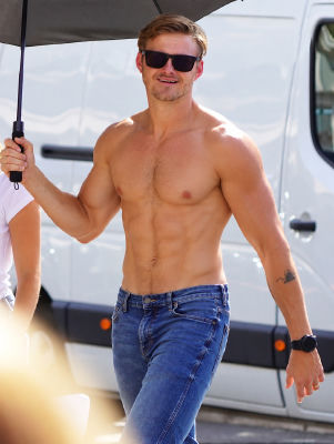 AI-generated image of Alexander Ludwig shirtless walking with an umbrella