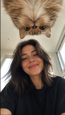 AI-generated selfie of a woman with a ginger cat peering down from above