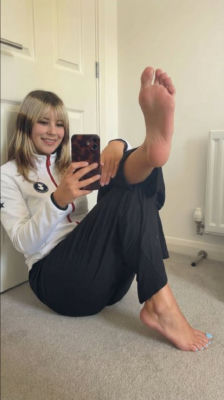 AI-generated mirror selfie alysa liu in a Team GB jacket with bare feet raised