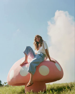 AI-generated image of an unidentified woman seated on a giant pink mushroom sculpture