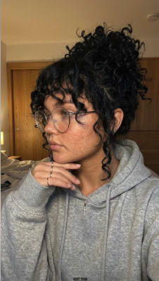 AI-generated selfie of a woman with curly hair and glasses