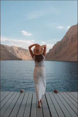AI-generated image of a woman in white standing on a lakeside deck