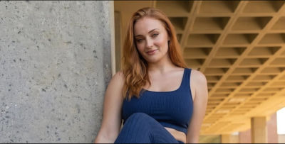 Deepfake of Sophie Turner seated under a concrete overhang