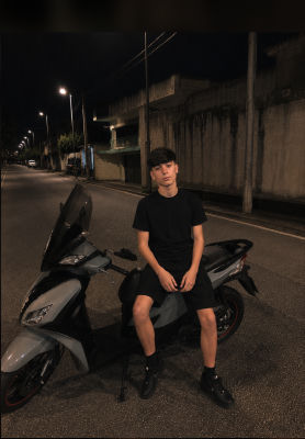 AI-generated image of an unidentified young man seated on a scooter at night