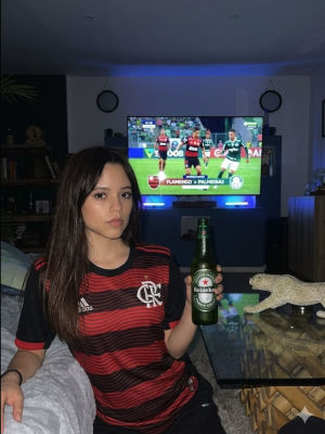 AI-generated image resembling Jenna Ortega in Flamengo jersey watching soccer match