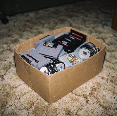 AI-generated image of retro video game consoles and controllers in a cardboard box