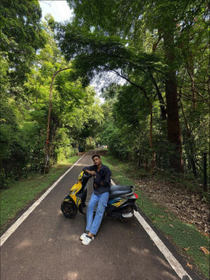 AI-generated photo of a man seated on a scooter on a tree-lined road