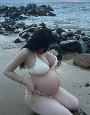AI-generated image of a pregnant woman in a bikini on a rocky beach