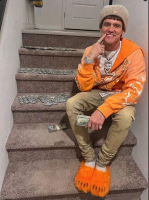 Deepfake of Jim Carrey as Lloyd Christmas posed on stairs with cash