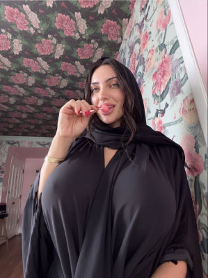 AI-generated selfie of a woman in a black hijab against floral wallpaper