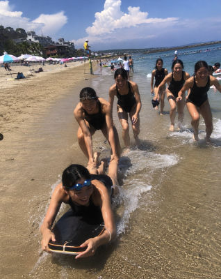 AI generated image of Young Swimmers Having Fun with a Board on a Sunny Beach Shoreline