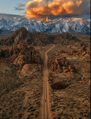 AI-generated landscape of a desert road toward snow-capped mountains at sunset