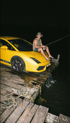 AI-generated image of a man fishing from a yellow Lamborghini on a wooden dock at night