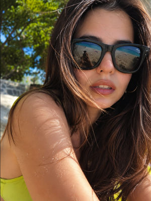 AI-generated beach selfie of an unidentified woman in sunglasses