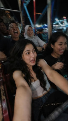 AI-generated selfie of an unidentified young woman on a night carnival ride