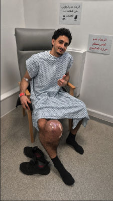 AI-generated image of a young man in a hospital gown with a knee injury