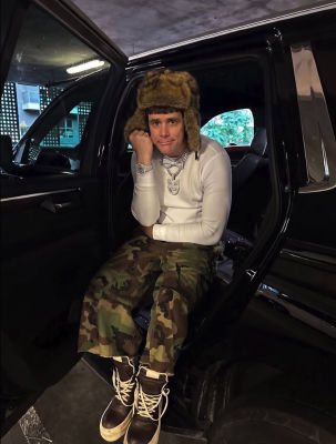 AI-generated image of Jim Carrey seated in a car doorway wearing a fur hat and camouflage pants