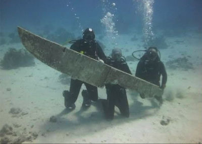 AI-generated image of scuba divers examining a large fin-shaped object underwater