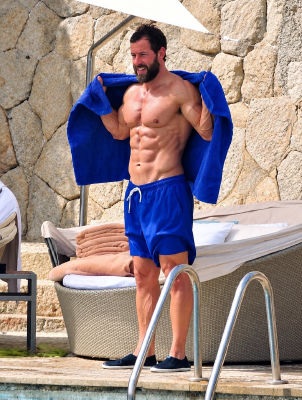 Deepfake image of Adam Sandler by a pool in blue swim trunks