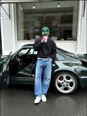 AI-generated image of a man drinking coffee beside a green Porsche