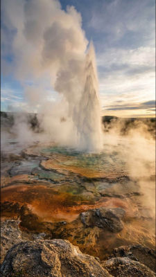 AI-generated image of a geyser erupting over colorful mineral terraces